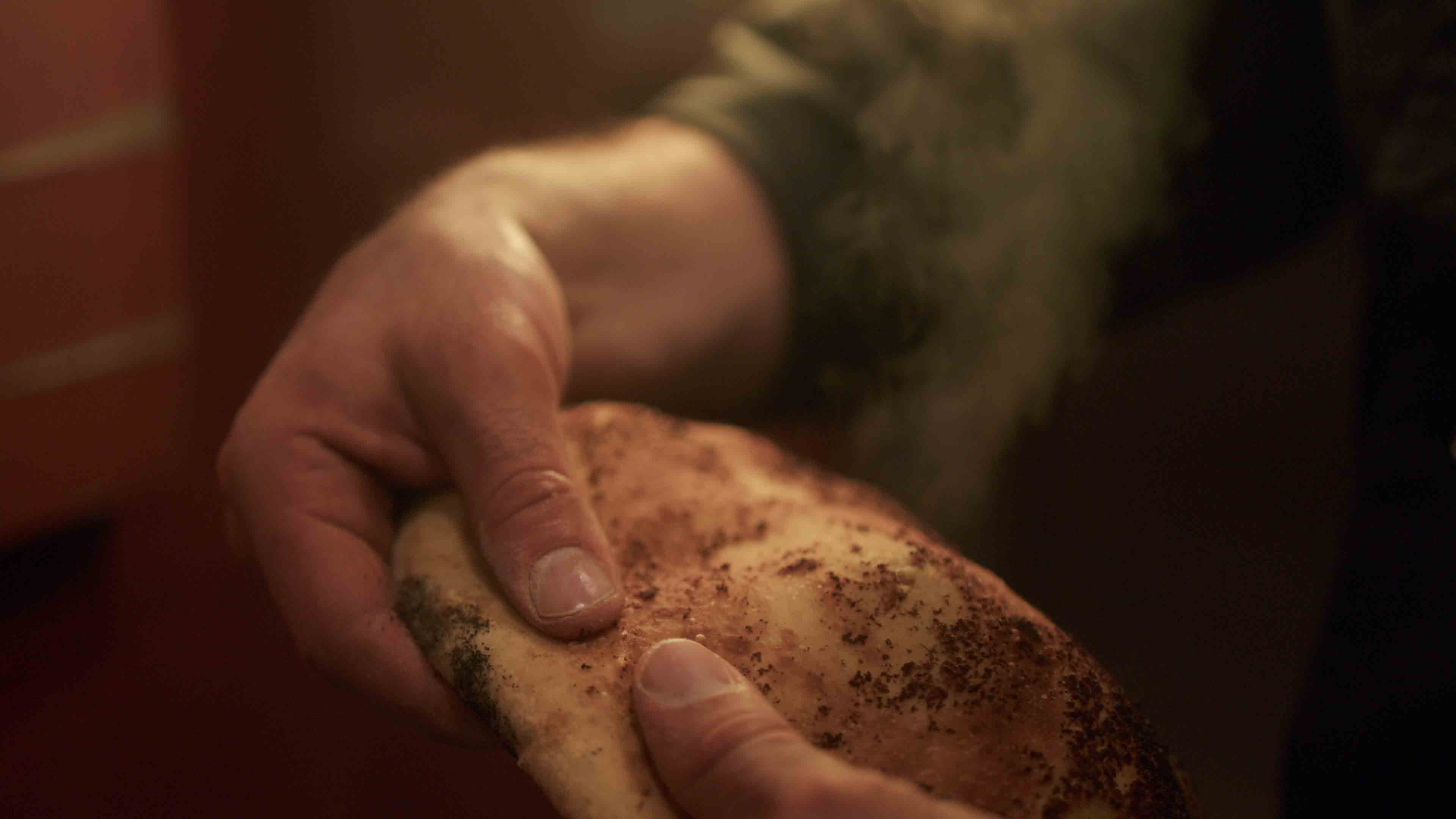 Zwei Hände, die ein Stück frisch gebackenes Fladenbrot halten, aus dem Dampf aufsteigt.